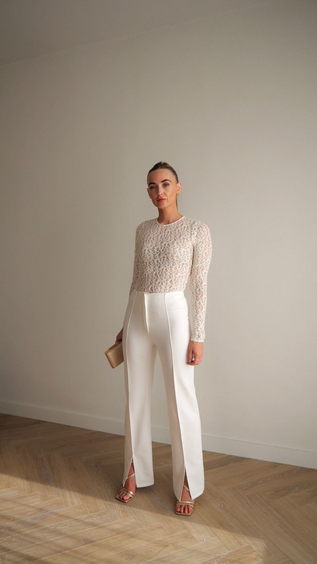 Full-length view of white tailored trousers with structured fit and refined detailing. Front slits add fluidity for an elevated silhouette. Designed by BOLDNSUBTLE.
