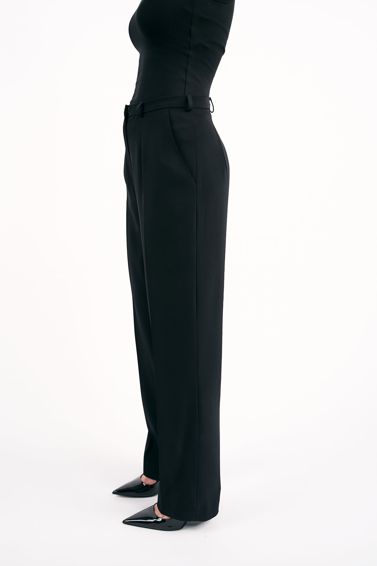 Black pants worn by a person on a white background