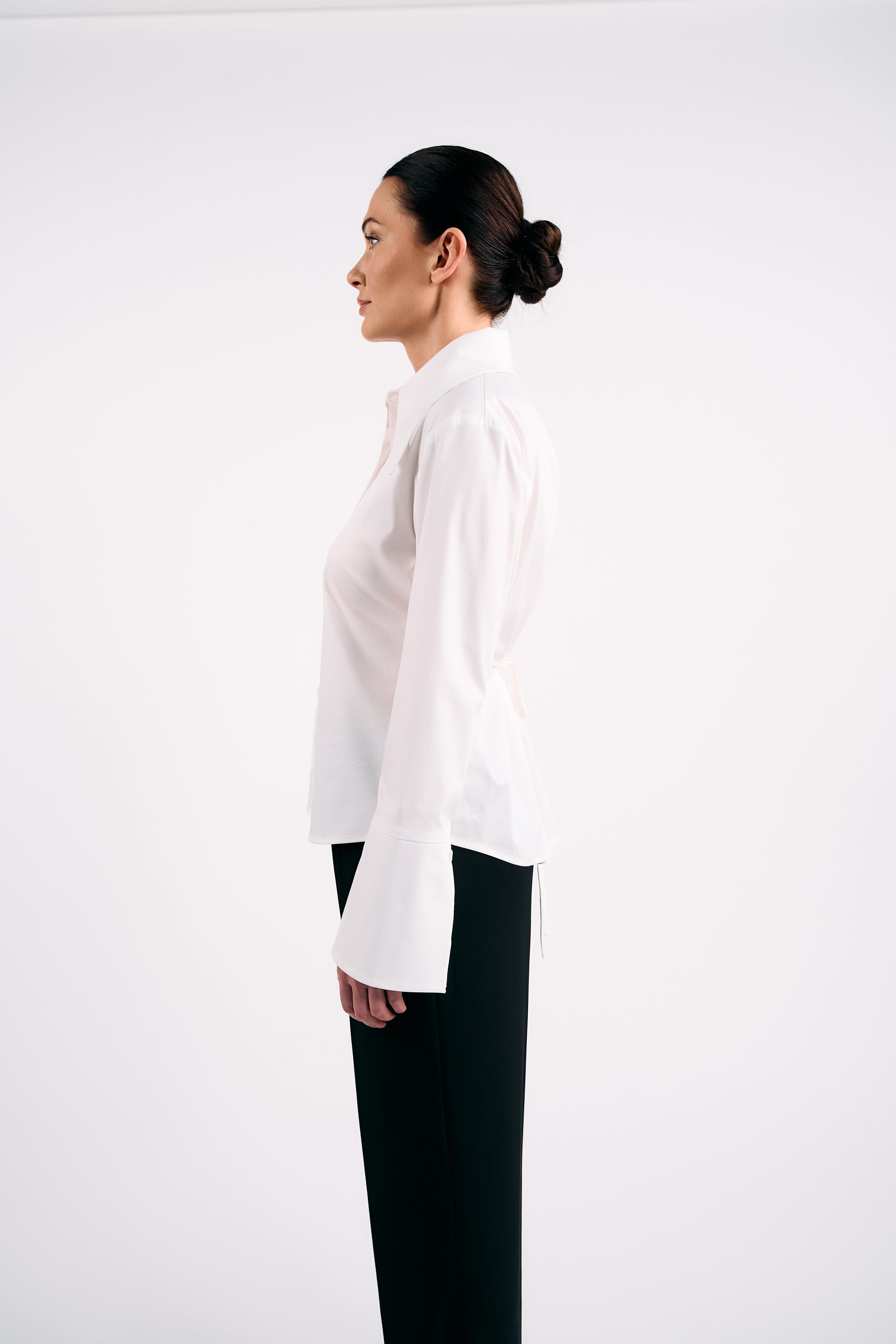 Woman wearing a white blouse and black trousers on a white background