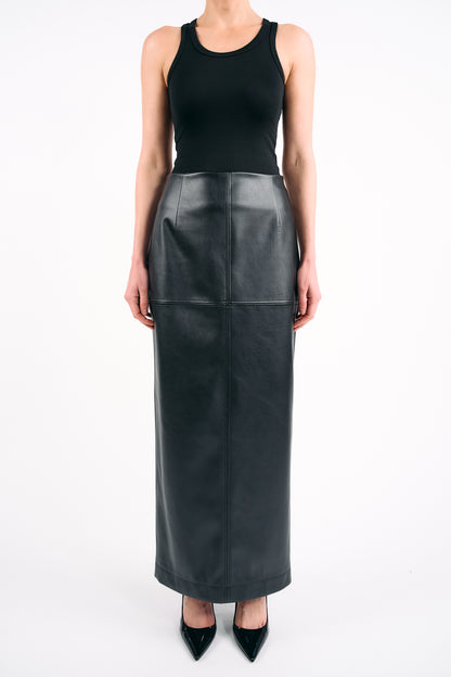 Black high-waisted PU maxi skirt styled with a fitted black tank top and pointed heels, photographed against a white background in a minimalist studio setting.