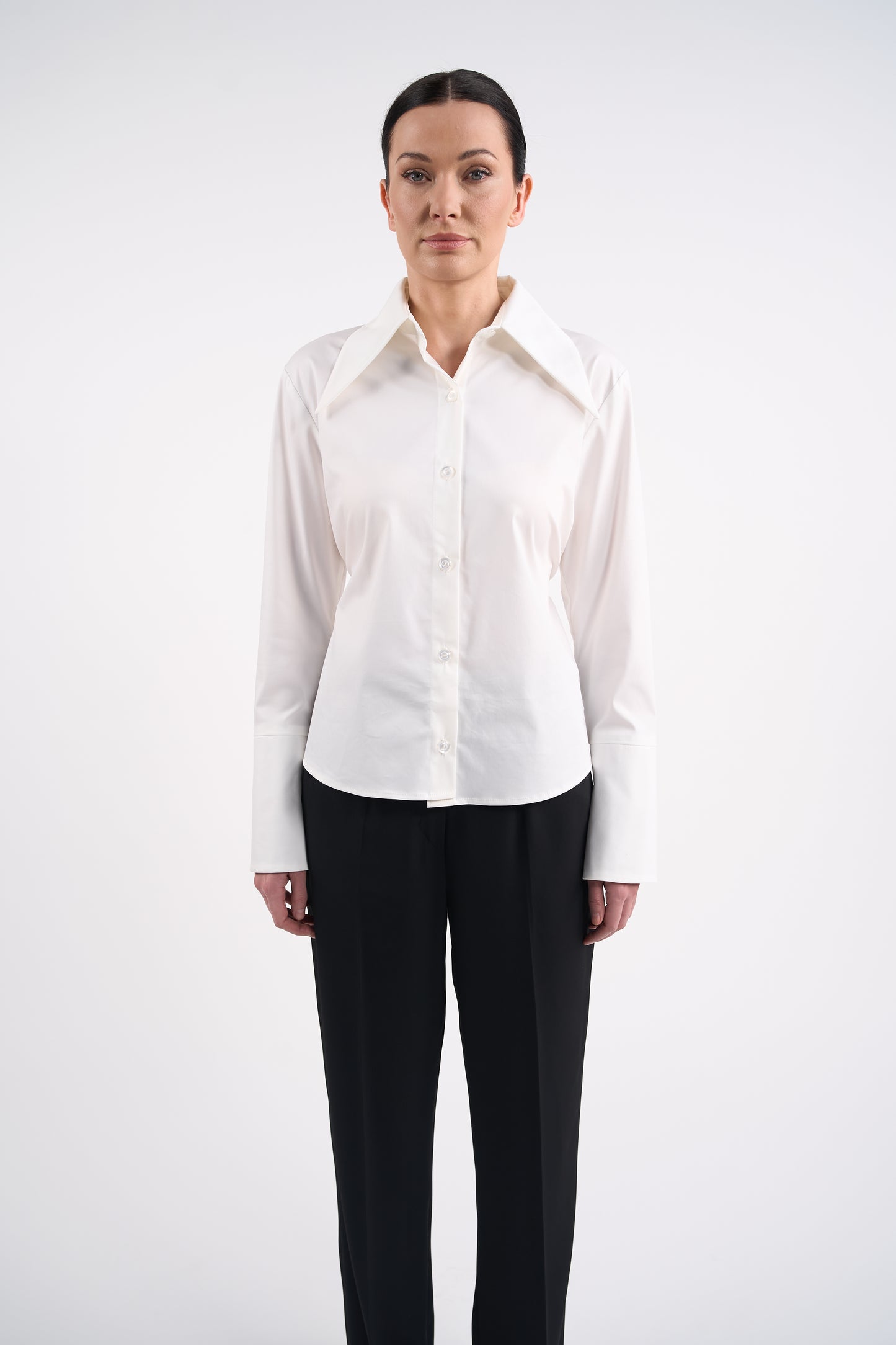 Woman wearing a white blouse and black trousers on a white background