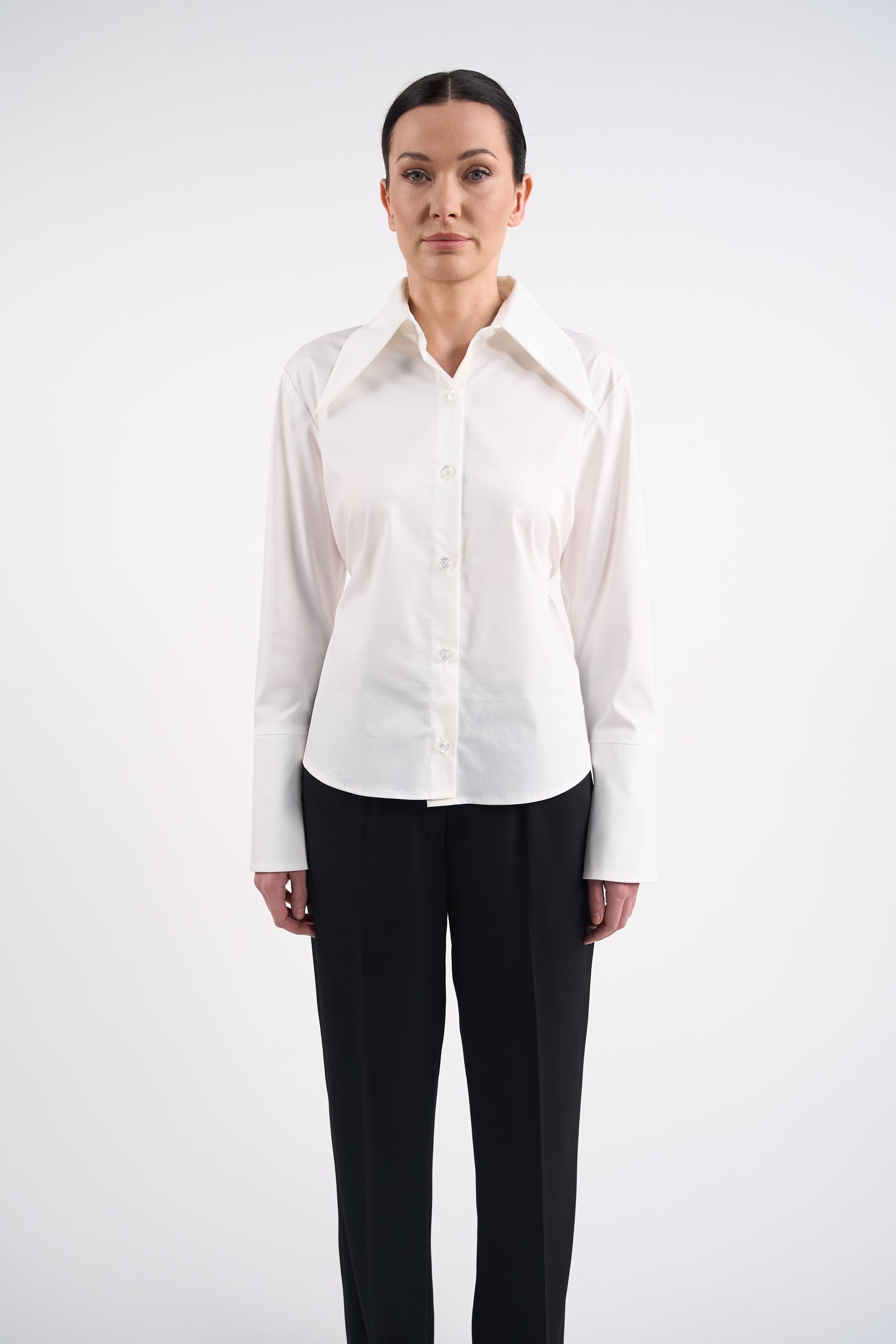 Woman wearing a white blouse and black trousers on a white background